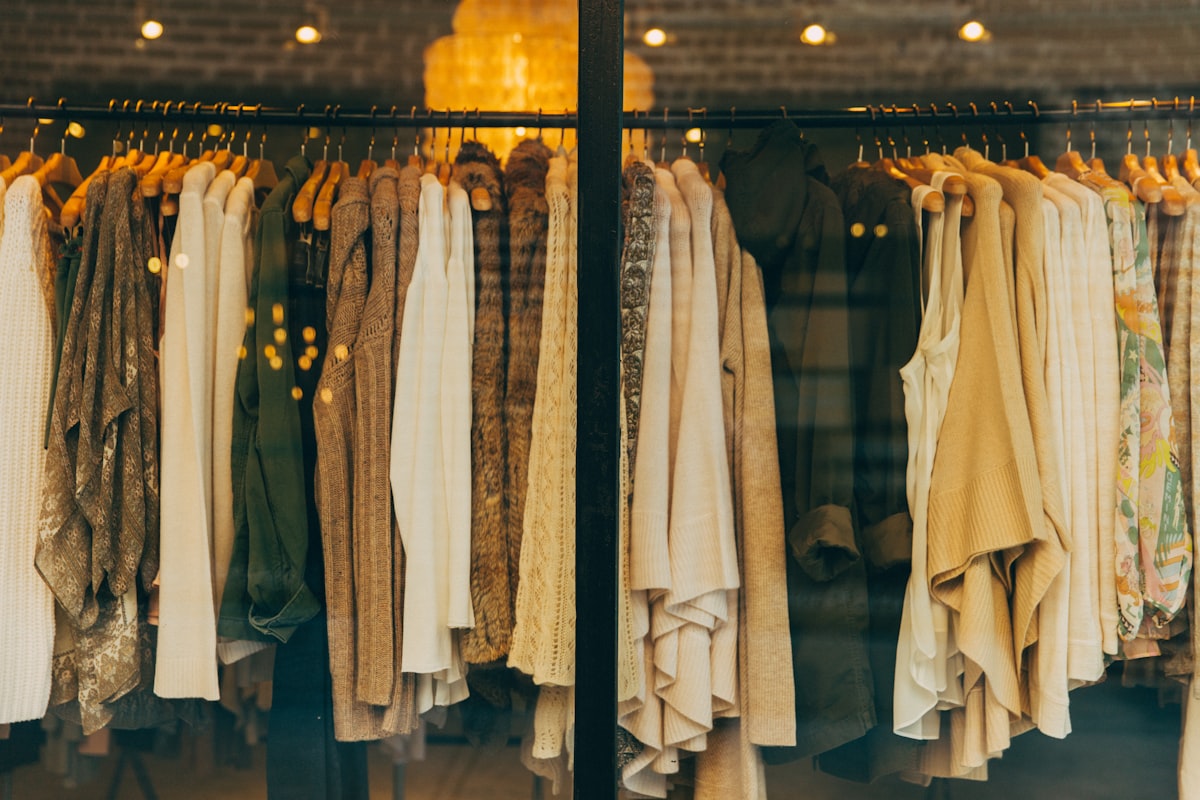 A rack of warm knitwear and jackets in a sunlit shop window